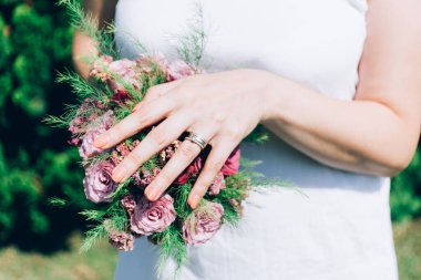 Gelin elinde güllerden bir buket tutuyor, düğün çiçekleri. Güzel bohem düğün çiçeği buketi. Bir buket gülü elbisesi olan kız..