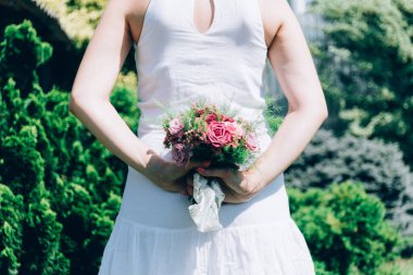 Bir buket şeftali güllü gelin boho stili. Düğün buketi gelinin elinde. Bir buket çiçekli beyaz elbiseli kız..