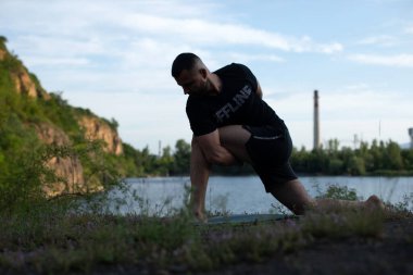 Doğada yoga yapan genç bir adam. Sağlıklı yaşam tarzı, meditasyon, yaşam tarzı konsepti. Uluslararası Yoga Günü