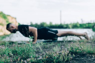 Sade, sakallı, siyah elbiseli, esneme sporu yapan, yoga yapan, spor yapan, spor yapan, spor yapan, spor yapan veya yeşil çimenlikte egzersiz yapan, esnek omurga egzersizi yapan çekici bir genç profili..