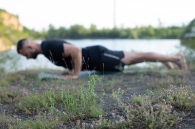 Sade, sakallı, siyah elbiseli, esneme sporu yapan, yoga yapan, spor yapan, spor yapan, spor yapan, spor yapan veya yeşil çimenlikte egzersiz yapan, esnek omurga egzersizi yapan çekici bir genç profili..