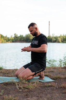 Sade, sakallı, siyah elbiseli, esneme sporu yapan, yoga yapan, spor yapan, spor yapan, spor yapan, spor yapan veya yeşil çimenlikte egzersiz yapan, esnek omurga egzersizi yapan çekici bir genç profili..