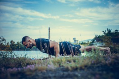 Sade, sakallı, siyah elbiseli, esneme sporu yapan, yoga yapan, spor yapan, spor yapan, spor yapan, spor yapan veya yeşil çimenlikte egzersiz yapan, esnek omurga egzersizi yapan çekici bir genç profili..