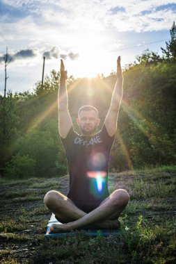 Mükemmel vücut adamının silueti günbatımı arka planında kayanın üzerinde yoga yapıyor. Uluslararası Yoga Günü.