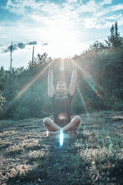 Mükemmel vücut adamının silueti günbatımı arka planında kayanın üzerinde yoga yapıyor. Uluslararası Yoga Günü.