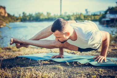 Genç bir adam güneşin altında taş ocağında yoga yapıyor. Yoga pozunda oturuyor. Denge, uyum, konsantrasyon ve rahatlama..