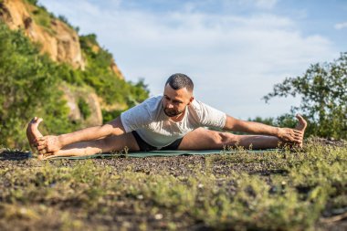 Genç fitness adamı taş ocağı gölünde yoga egzersizi yapıyor. Sakallı yakışıklı genç adam yoga egzersizi yapıyor..