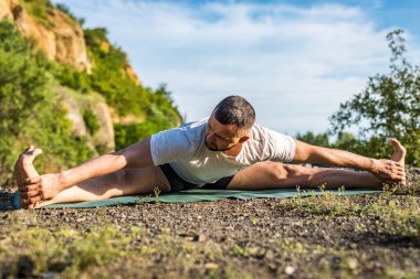 Genç fitness adamı taş ocağı gölünde yoga egzersizi yapıyor. Sakallı yakışıklı genç adam yoga egzersizi yapıyor..