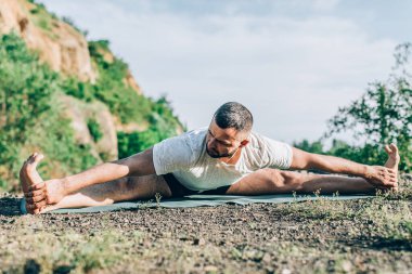 Genç fitness adamı taş ocağı gölünde yoga egzersizi yapıyor. Sakallı yakışıklı genç adam yoga egzersizi yapıyor..