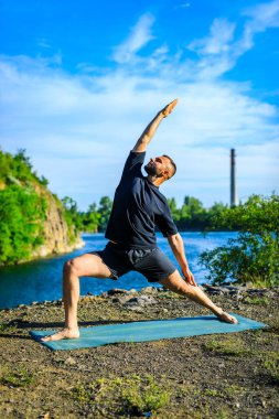 Güneşli bir günde taş ocağı gölünde yoga egzersizi yapan adam. Uluslararası Yoga Günü.