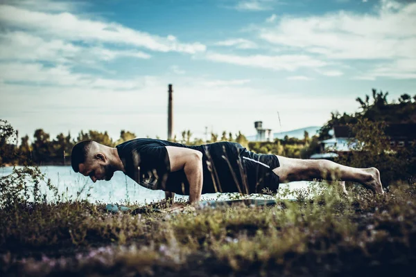 Sade, sakallı, siyah elbiseli, esneme sporu yapan, yoga yapan, spor yapan, spor yapan, spor yapan, spor yapan veya yeşil çimenlikte egzersiz yapan, esnek omurga egzersizi yapan çekici bir genç profili..