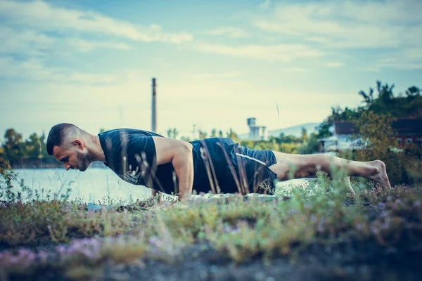 Sade, sakallı, siyah elbiseli, esneme sporu yapan, yoga yapan, spor yapan, spor yapan, spor yapan, spor yapan veya yeşil çimenlikte egzersiz yapan, esnek omurga egzersizi yapan çekici bir genç profili..