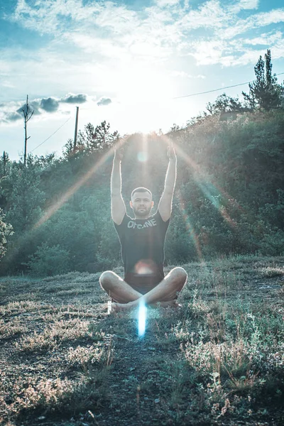Mükemmel vücut adamının silueti günbatımı arka planında kayanın üzerinde yoga yapıyor. Uluslararası Yoga Günü.