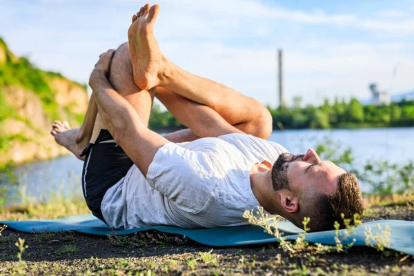 Sabah parkında yoga yapan genç bir adam. Sakallı adam rahatla ve doğada esne. Uluslararası Yoga Günü