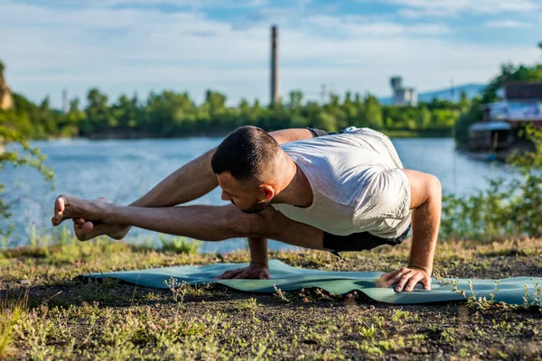 Genç bir adam güneşin altında taş ocağında yoga yapıyor. Yoga pozunda oturuyor. Denge, uyum, konsantrasyon ve rahatlama..