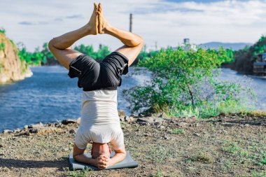 Parkta yoga yapan yakışıklı atletik adam. Quarry Gölü geçmişi. Uluslararası Yoga Günü.
