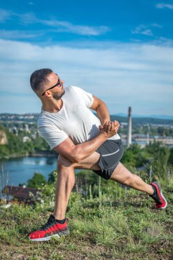 Profesyonel fitness eğitmeni. Sakallı sporcu antrenman yapıyor, taş ocağı gölünde geriniyor. Açık hava spor konsepti.