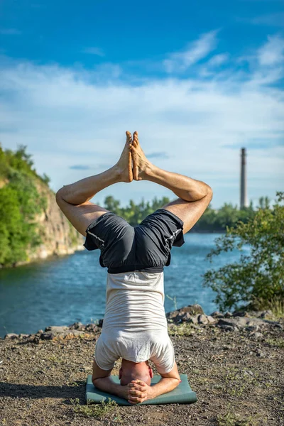 Parkta yoga yapan yakışıklı atletik adam. Quarry Gölü geçmişi. Uluslararası Yoga Günü.