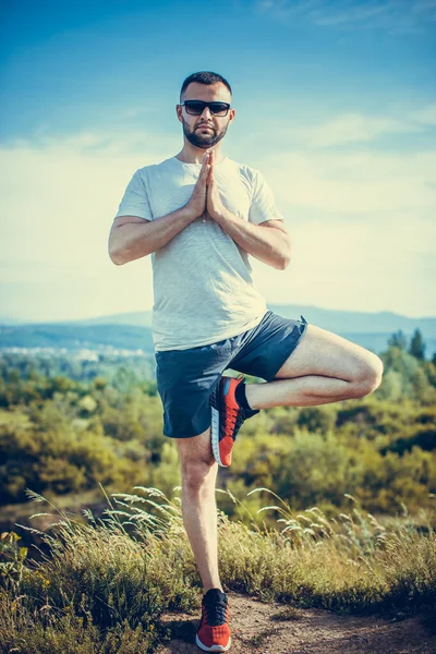 Genç sakallı gezgin ayakları arkasında günbatımı dağlarıyla tek başına duruyor. Yaşam tarzı seyahat kavramı.