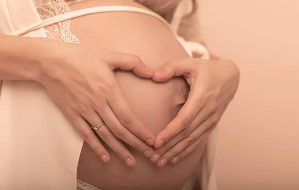 Zbliżenie Kobiety Ciąży Trzymającej Ręce Jej Spuchniętym Brzuchu Kształtującym Serce — Zdjęcie stockowe