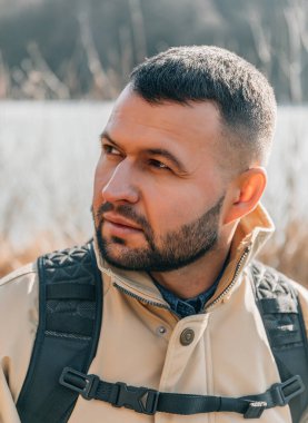 Gölün yanındaki kütüğün üzerinde oturan sakallı bir adamın portresi. Beyaz adam gölde tek başına oturuyor ve bir yaz günü manzaraya bakıyor..