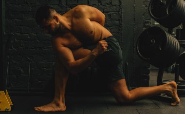 Orta yaşlı çekici bir adam yoga konsepti uyguluyor, zor bir pozisyonda oturuyor, siyah spor kıyafetleri giyiyor. Sağlıklı yaşam tarzı kavramı.