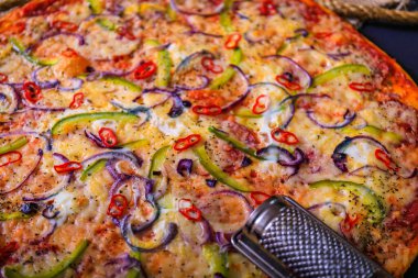 Geleneksel İtalyan pizzası, sebzeler, koyu taşlı arka planda malzemeler. Pizza fırında pişiyor. Pizza menüsü. Yukarıdan bak. Metin için boşluk.