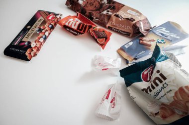 Lviv / Ukraine - April 2020: Assorted candy, cookie and chocolate wrappers left on a white table. Delicious sweets full of sugar that leads to health issues and overweight. Binge eating in isolation. clipart