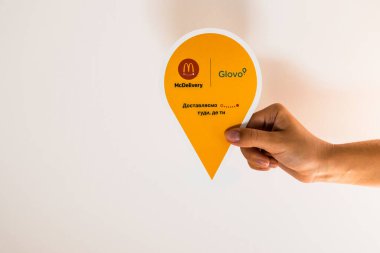 Lviv / Ukrayna - Nisan 2020: Glovo dağıtım servisi etiketi beyaz duvara karşı. Sosyal izolasyon sırasında evden yemek sipariş etmek. Parlak turuncu logo. Kuryeler McDelil getiriyor..
