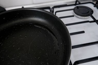Gaz sobasında kalan yağlı, siyah kızartma tavası. Yemek pişirdikten sonra yıkanmamış dağınık yemek takımı. Sağlıksız yemek seçimleri ve obeziteye yol açan yaşam tarzı. Mutfaktaki yağlı yağlı yemek yüzeyi..