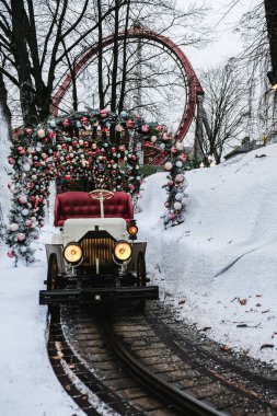 Kopenhag / Danimarka - Kasım 2019: Tivoli Gardens lunaparkında Noel temalı tren. İnsanlar yok, farlar açık ve kış tatilinde kar yağıyor. İzole edilmiş üzgün tren..