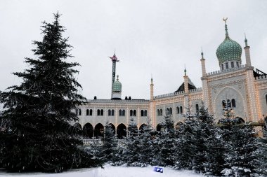 Kopenhag / Danimarka - Kasım 2019: Tivoli Bahçeleri 'ndeki güzel butik Nimb Oteli Noel için süslendi. Beyaz Mağribi Sarayı kış mevsiminde vurgulandı. Turistler için karlı bir peri masalı havası.
