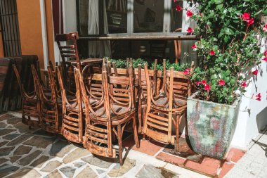 İspanya 'da kapalı bir kafe yakınlarında bir sürü sandalye. Güneşli bir günde dış görünüş. Sabahın erken saatlerinde, etrafta ziyaretçi ya da turist yoktu. İnsansız ve kapalı işyerlerinin olduğu boş İspanyol caddesi..