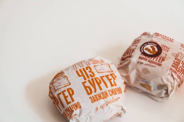 Lviv / Ukrayna - Nisan 2020: Evdeki beyaz bir masada Ukrayna Mcdonalds 'tan iki çizburger. Koronavirüs salgını sırasında sağlıksız yiyecekler. Tecritteyken yemek siparişi vermek. Beyaz boşluk kaldı.