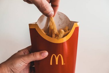 Lviv / Ukrayna - Nisan 2020: Aç adamın McDonalds 'ın çantasından bir parça patates kızartması alırken görüntüsünü kapatın. Coronavirus salgını sırasında evden sağlıksız yemek siparişi vermek..