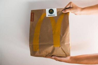 Lviv / Ukrayna - Nisan 2020: İki el McDonalds paket yiyecek getiriyor. Coronavirus salgını sırasında evde sağlıksız yiyecekler. Kurye akşam yemeği için internetten sipariş getiriyor..