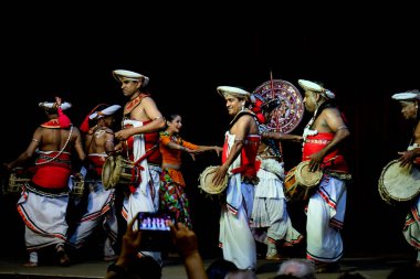 Kandy / Sri Lanka - Şubat 2020: Sri Lankalı performansı. Geleneksel parlak elbiseli yerel sanatçılar sahnede gösteri yapıyorlar. Dans eden kadınlar ve davul çalan erkekler.