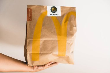 Lviv / Ukrayna - Nisan 2020: Coronavirus salgını sırasında evde sağlıksız yemek. Kurye McDonalds 'dan bir kese kağıdı veriyor. Evden izolasyon sırasında yemek siparişi vermek.