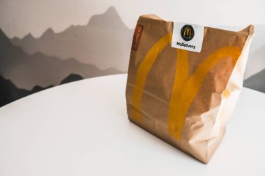 Lviv / Ukrayna - Nisan 2020: Coronavirus salgını sırasında evde sağlıksız yemek. McDonalds 'ın yemeğini sipariş etmek. Masada boş beyaz alan olan bir kesekağıdına. Ukrayna 'da teslimat hizmeti.