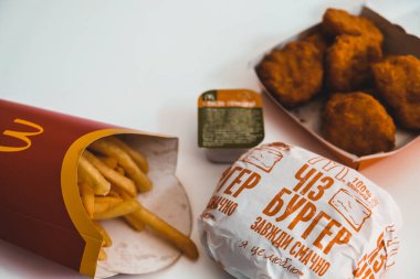 Lviv / Ukrayna - Nisan 2020: Ukrayna Mcdonalds 'dan gelen tüm yemek evdeki beyaz bir masada. Koronavirüs salgını sırasında sağlıksız yiyecekler. Tecritteyken yemek siparişi vermek. Kopyalamak için beyaz boşluk.