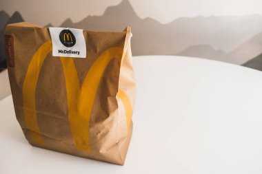 Lviv / Ukrayna - Nisan 2020: Coronavirus salgını sırasında evde sağlıksız yemek yeme sosyal izolasyonu. McDonalds 'ın yemeğini sipariş etmek. Evdeki bir masada kağıt torba. Fast food teslimatı.