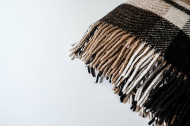 Beyaz masa yüzeyinde uzun kenarlı kahverengi ekose battaniye. İç tasarımda tekstil. İzolasyonda çalışırken ya da evde çalışırken örtbas etmek için sıcak malzemeler ısıtıyorum. Evde sonbahar titreşimleri.