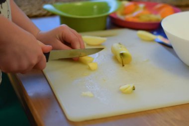 Bir çocuk mutfakta bir bıçakla bir elma keser..