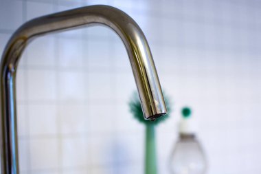 Beyaz duvar arka planında mutfak musluğu. Yakın plan.