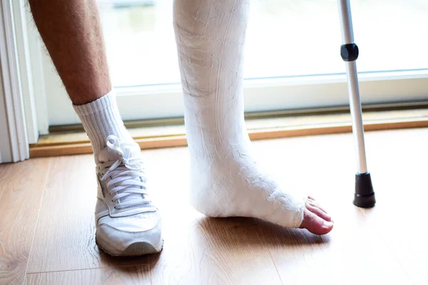 A man with a cane with a broken leg in a cast.