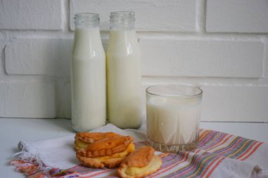 Bir şişe süt ve arka planda bir bardak süt.