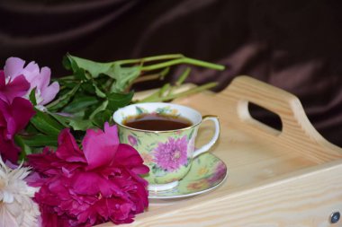 Bir tepsi çay ve yatakta bir buket şakayık