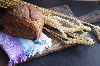 Ahşap mutfak tahtasının üzerinde taze çavdar ekmeği ve kulaklar.