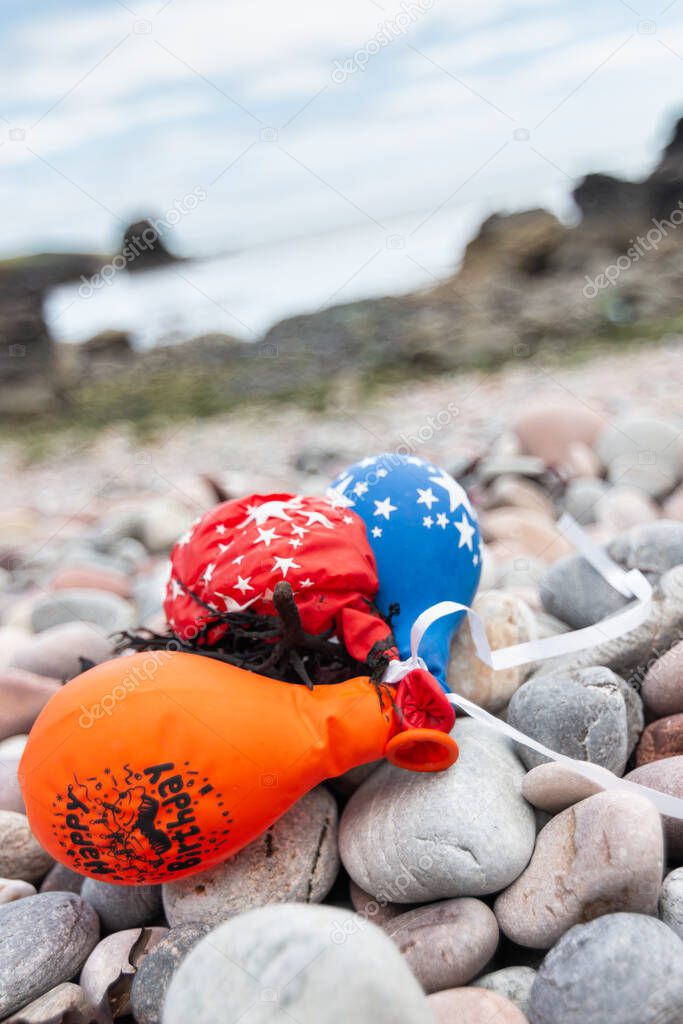 Party balloons which have drifted and landed on a rocky beach