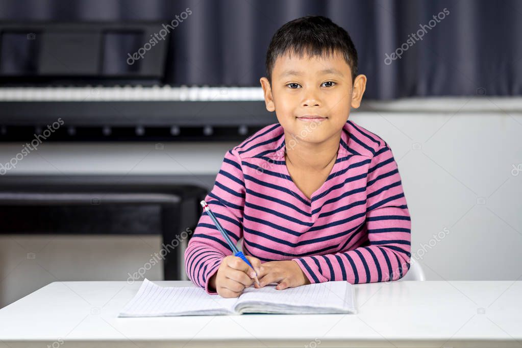 Young Asian boy write on the note book by pencil in the room